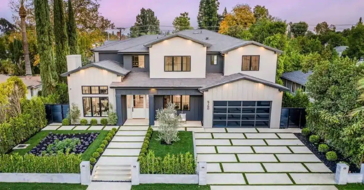 Modern two-story house with gray and white exterior, large windows, and landscaped front yard after home exterior remodelling.