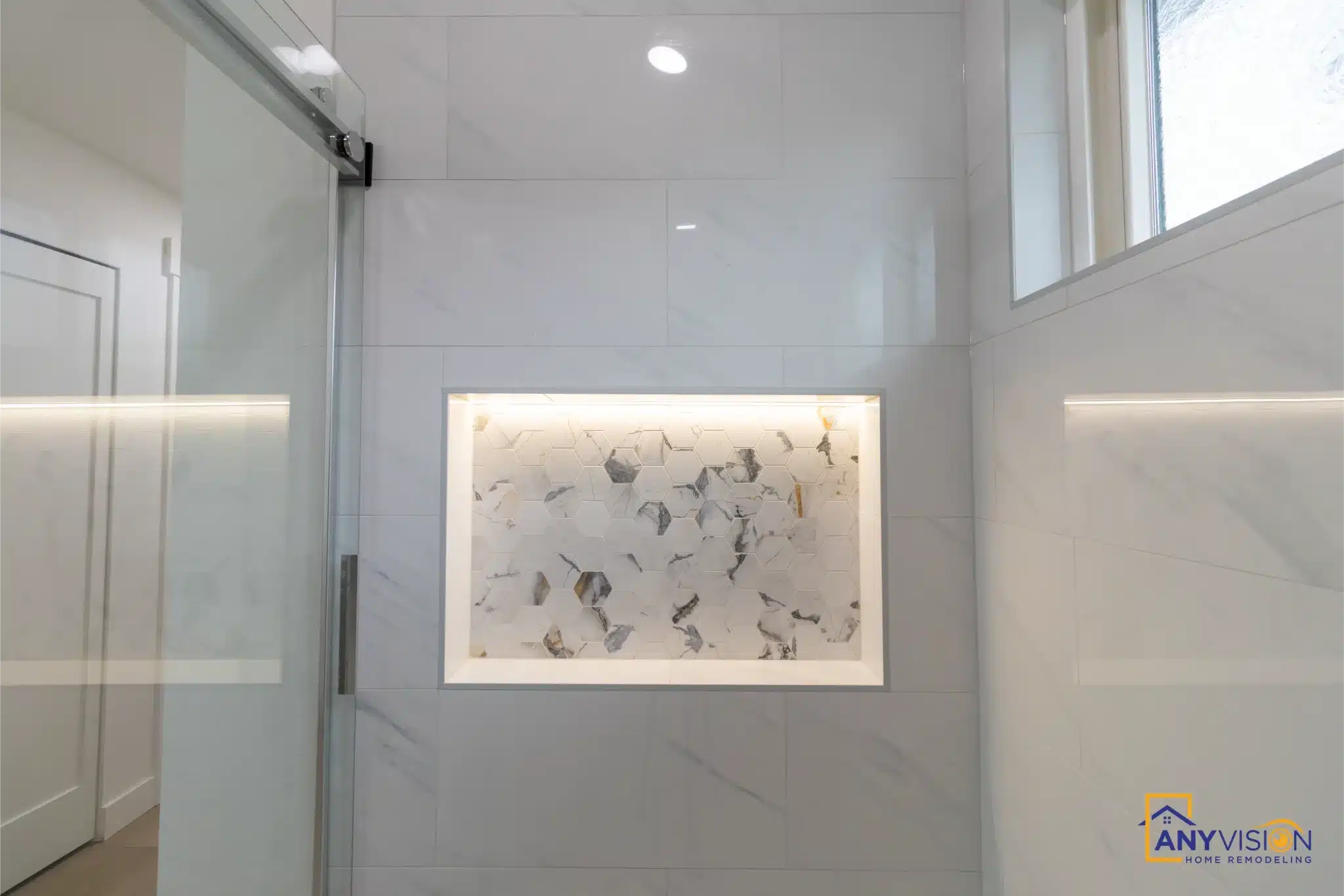 Primary bathroom with mosaic tile, frameless glass shower and LED-lit niche