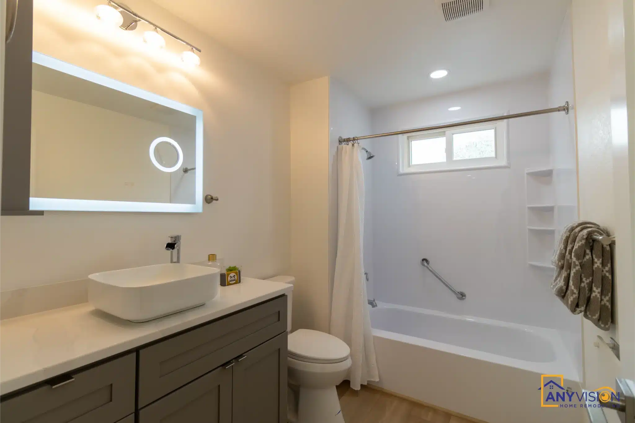 Second bathroom with bath, vanity and backlit mirror