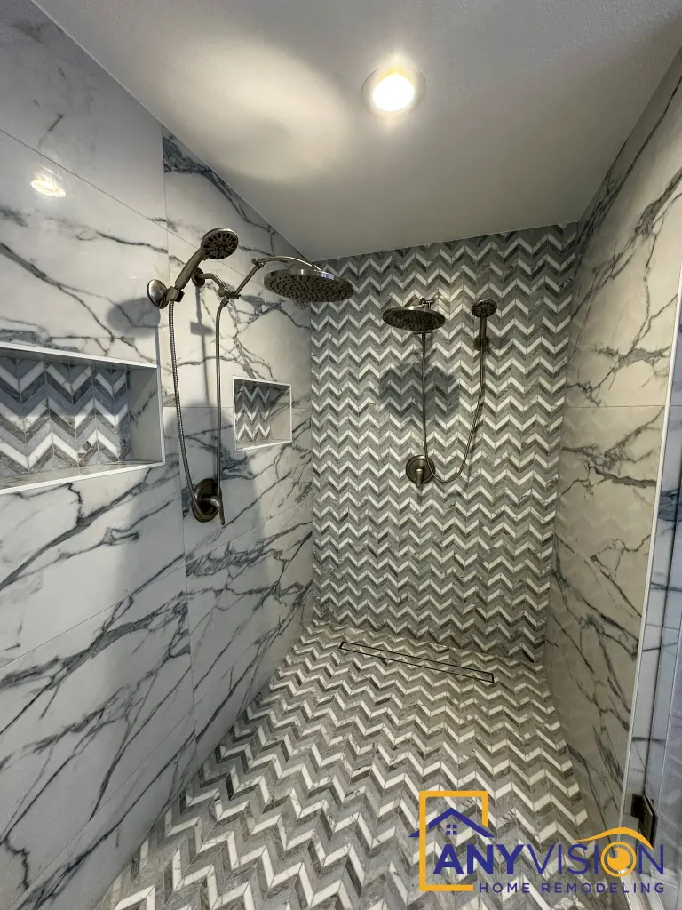 Walk-in shower with matte black fixtures against book-matched slab
