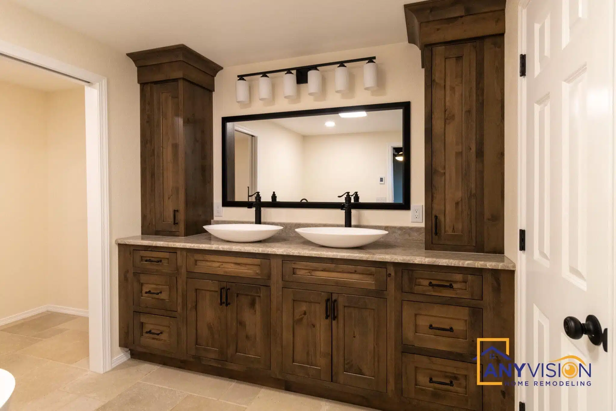 Dark wood double vanity with a large framed mirror and wall sconces