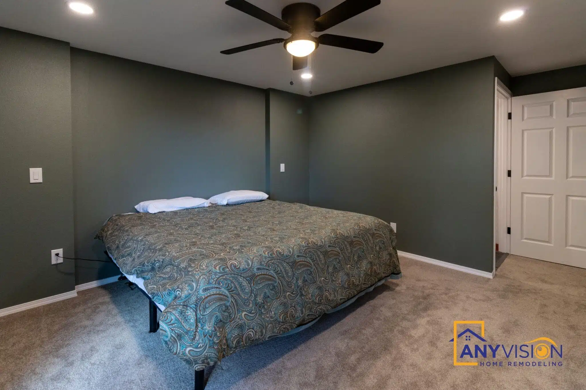 Primary bedroom with ceiling fan and a deep green feature wall