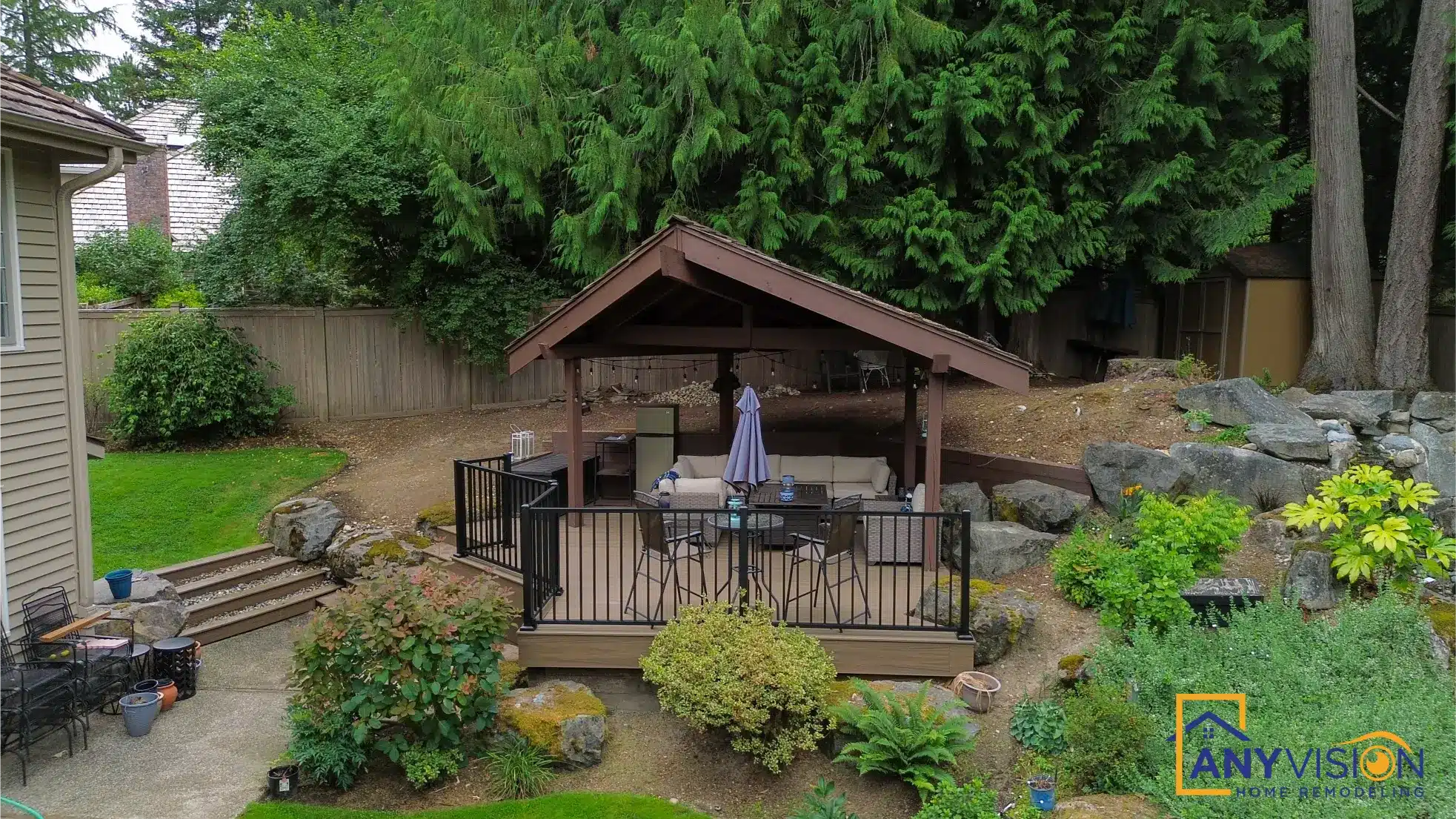 Covered pavilion seated among mature trees and rockery planting