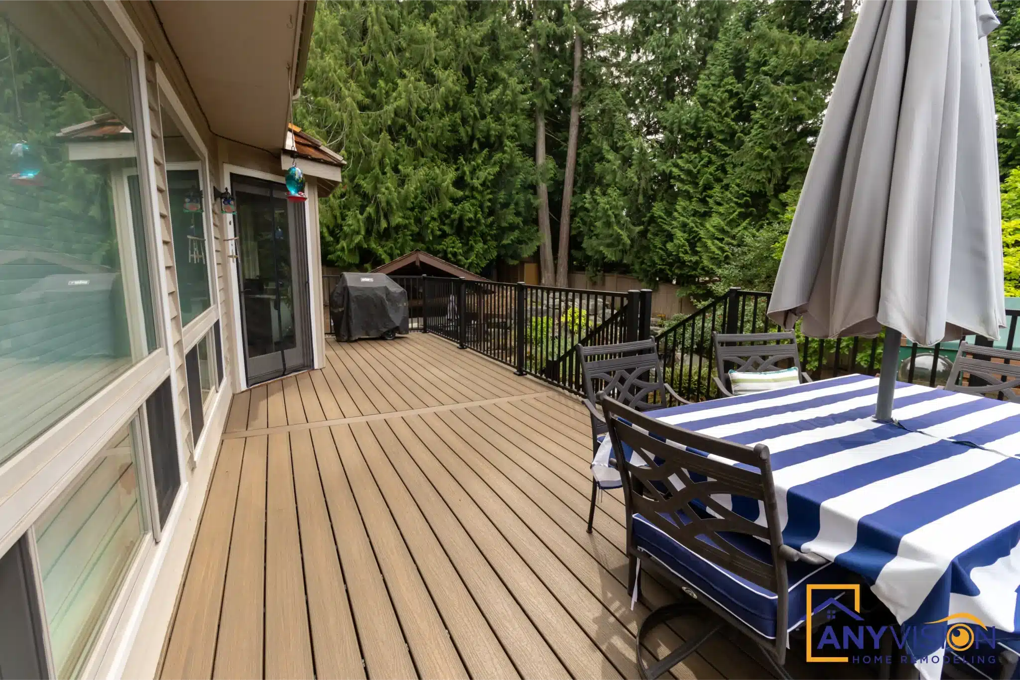 Upper deck with dining table and umbrella running alongside the house