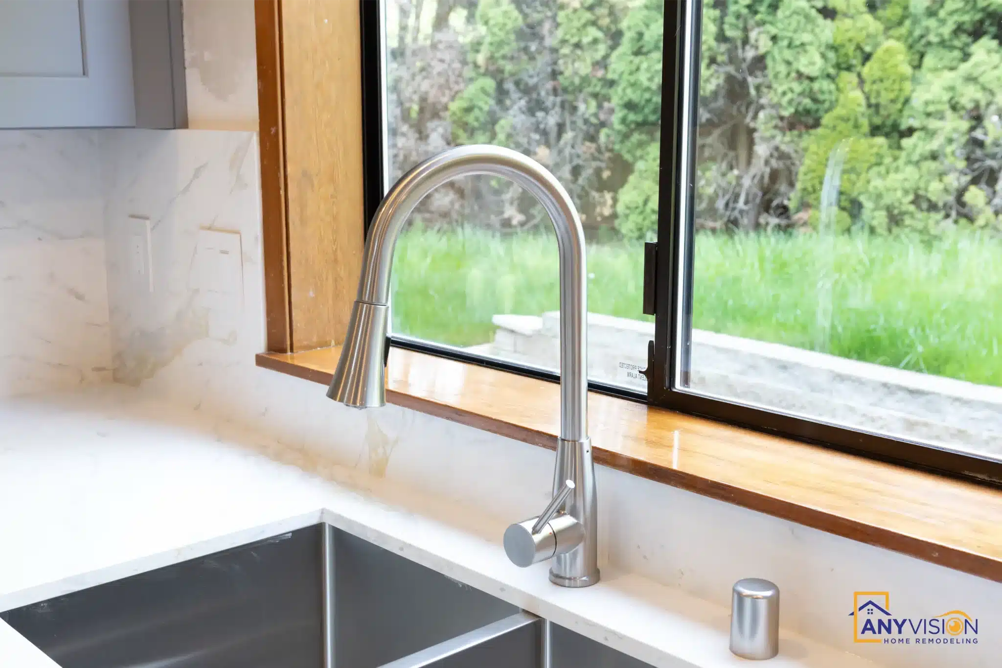 Brass gooseneck tap over the undermount sink beneath the window