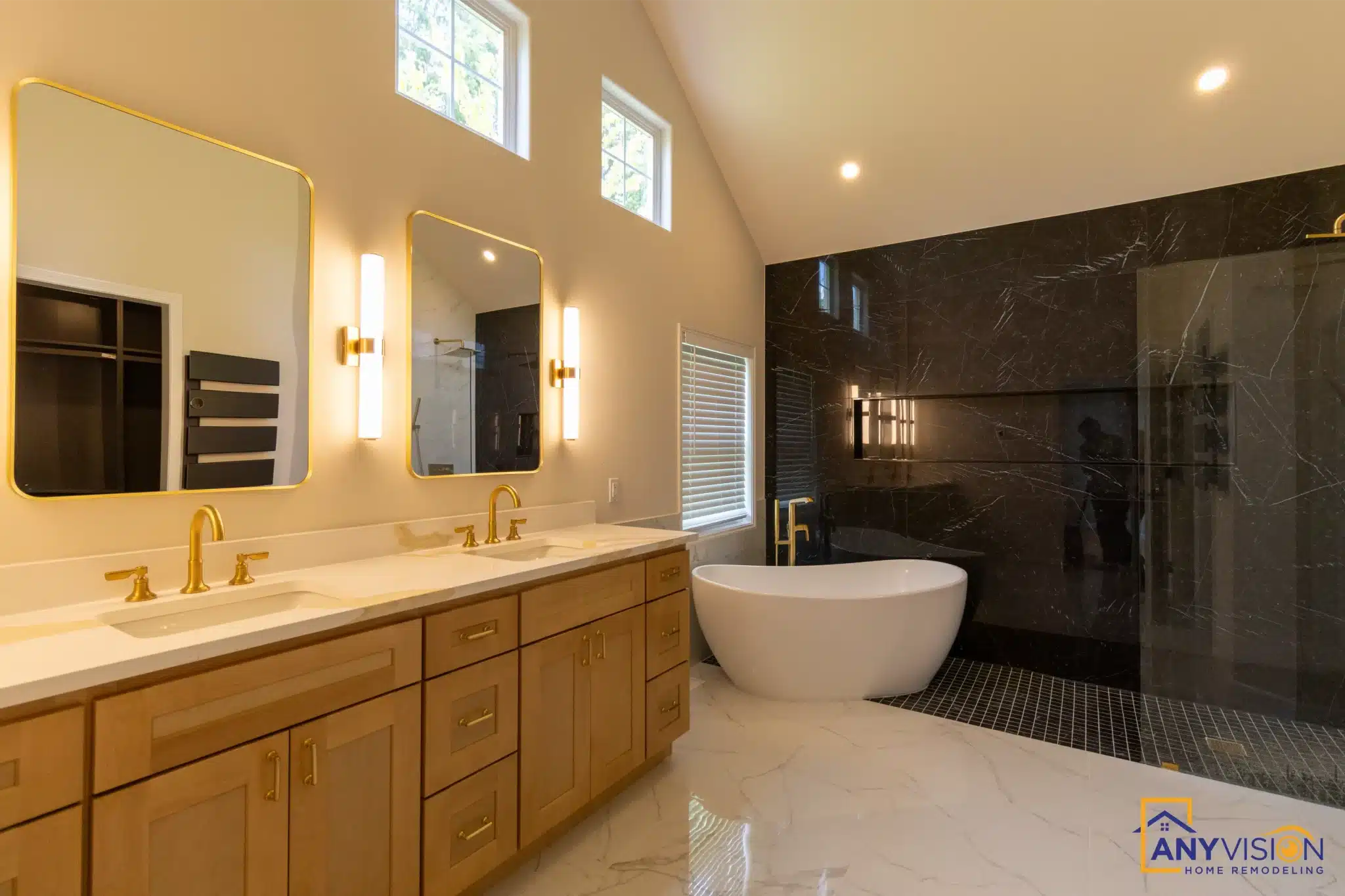 Primary bathroom with oak double vanity, freestanding tub and black marble wall