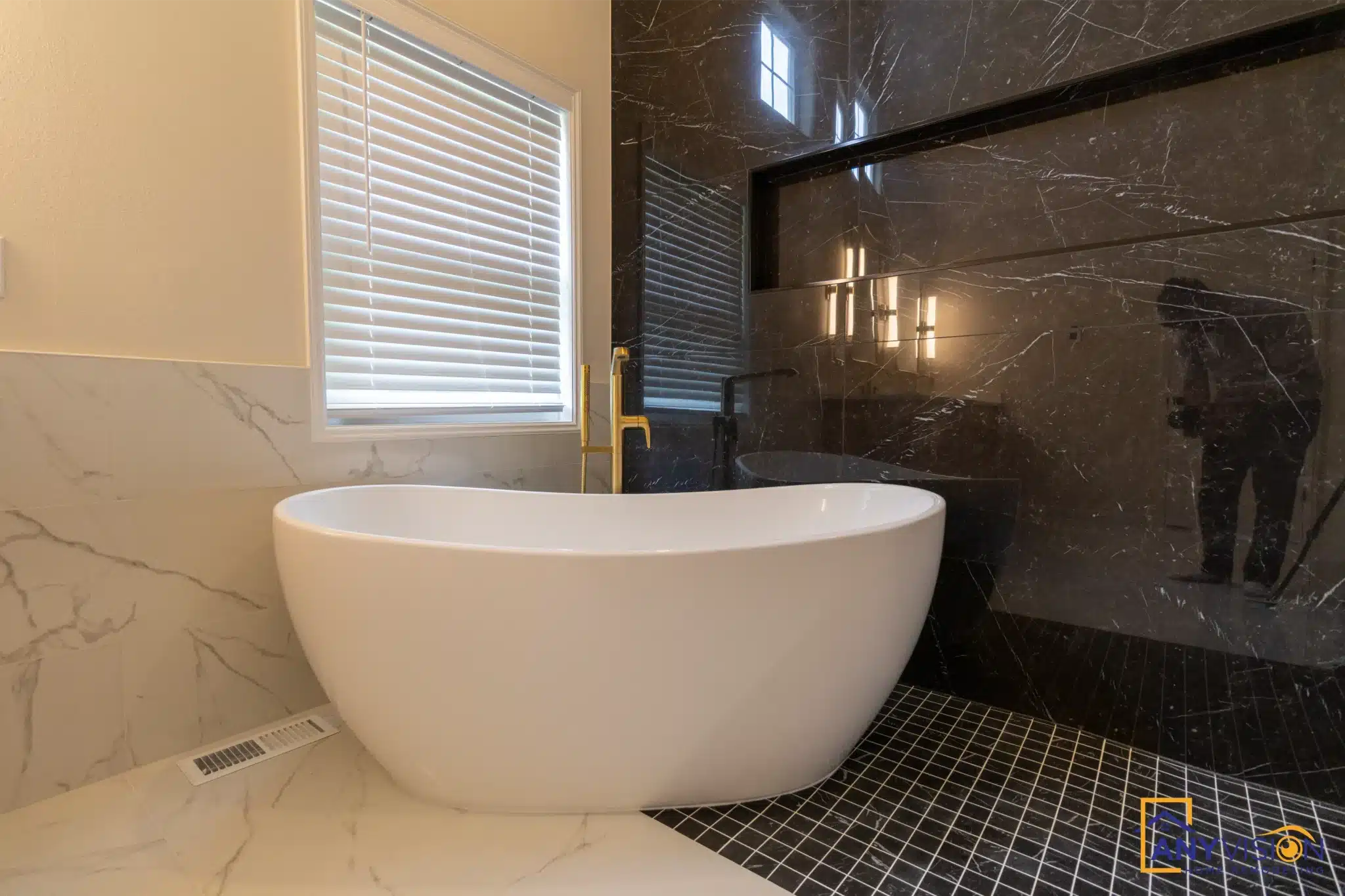 Freestanding tub with brass filler against the black marble surround