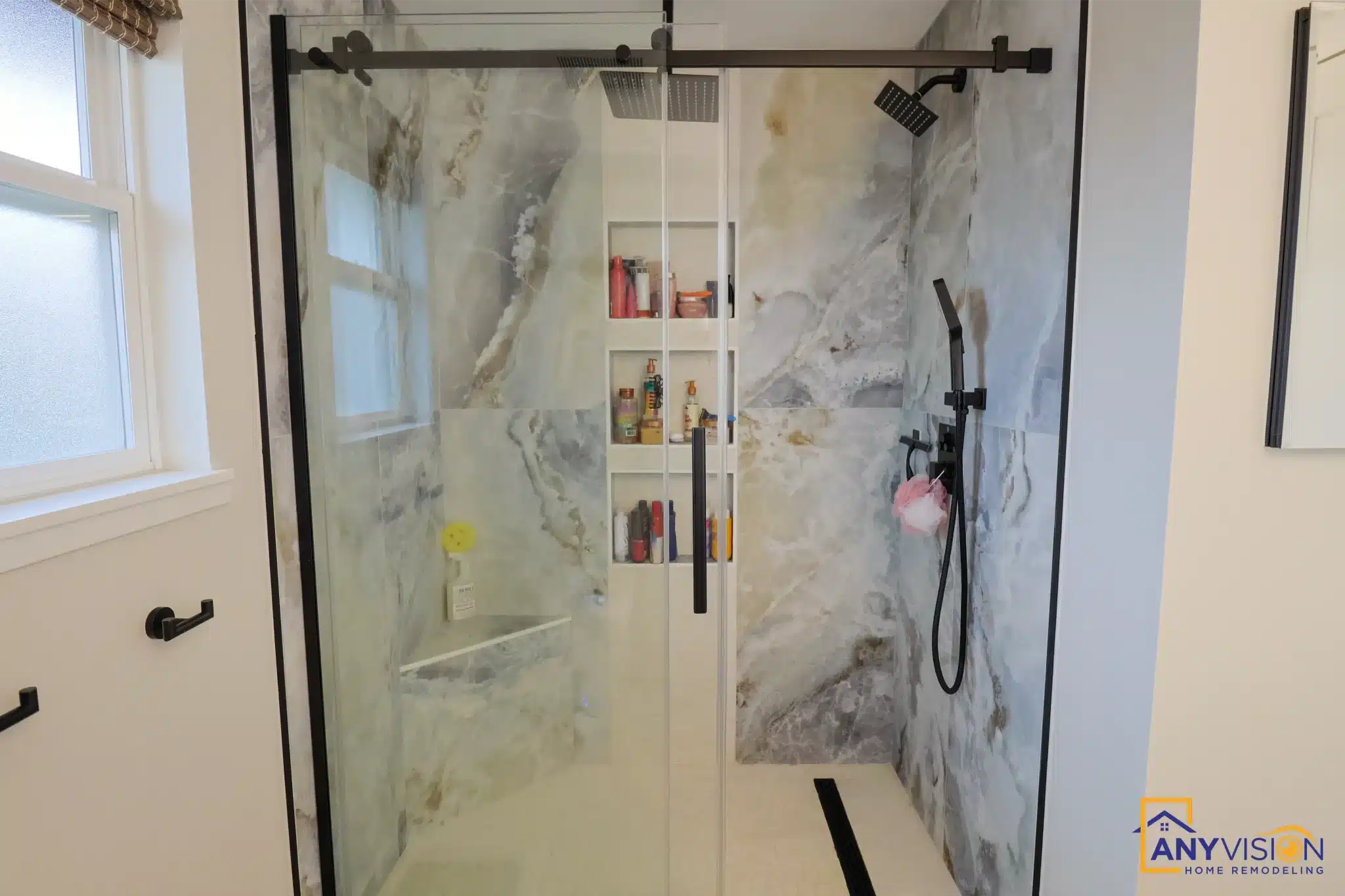 Black-framed glass shower enclosure with recessed niche and handheld