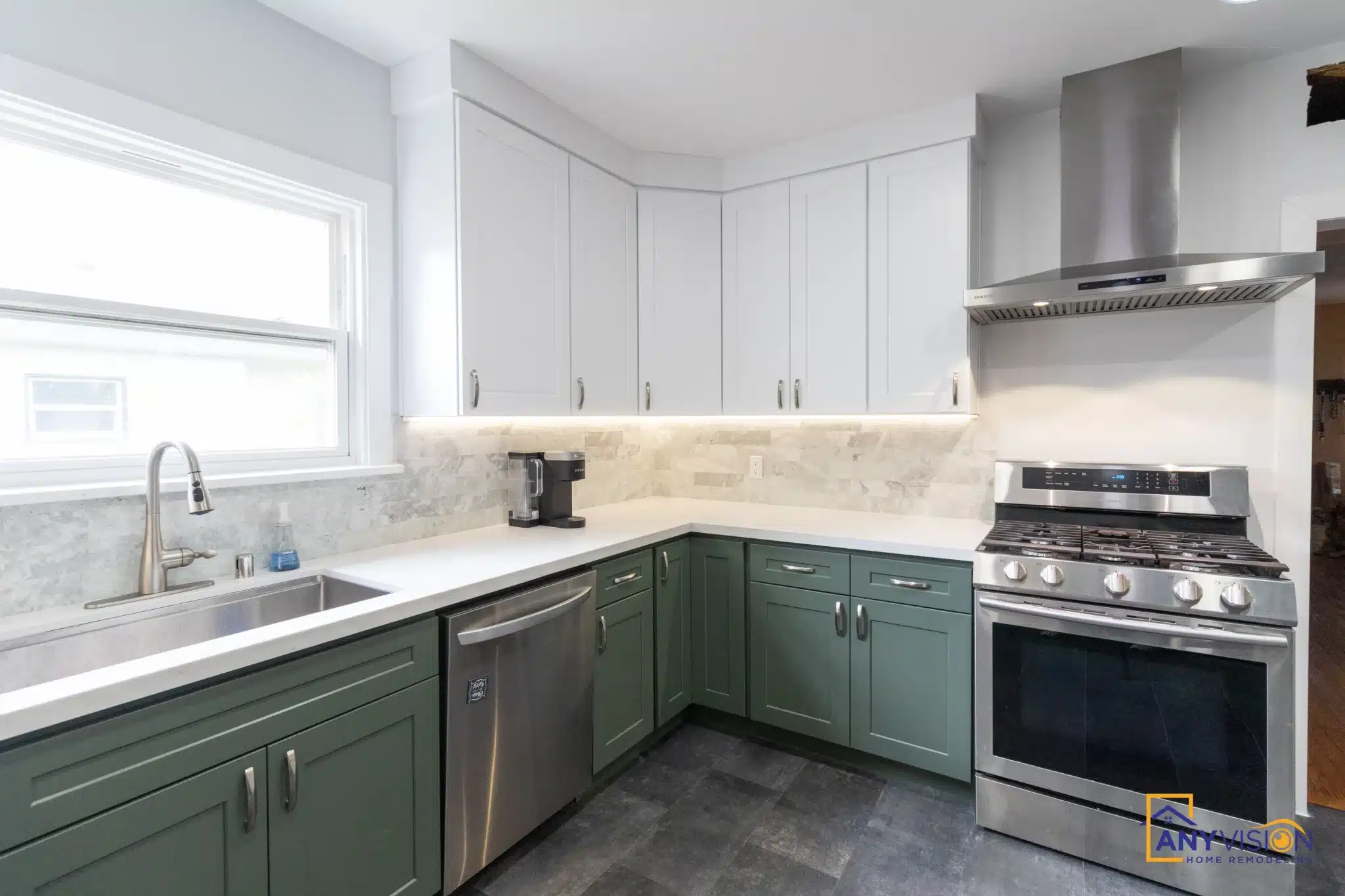 Counter run with the stone backsplash between green base cabinets and white uppers