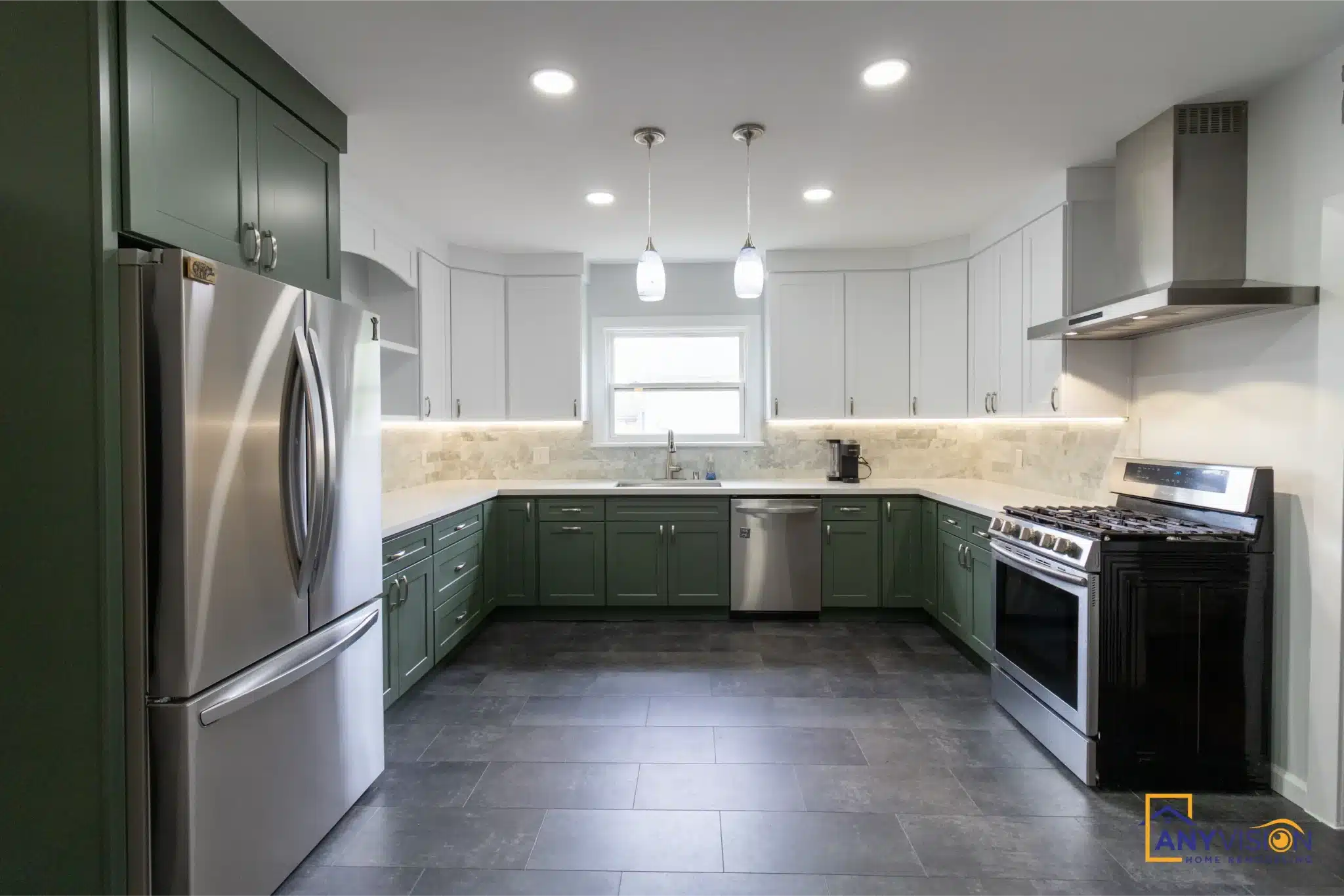 Green base cabinets and white uppers seen down the length of the kitchen