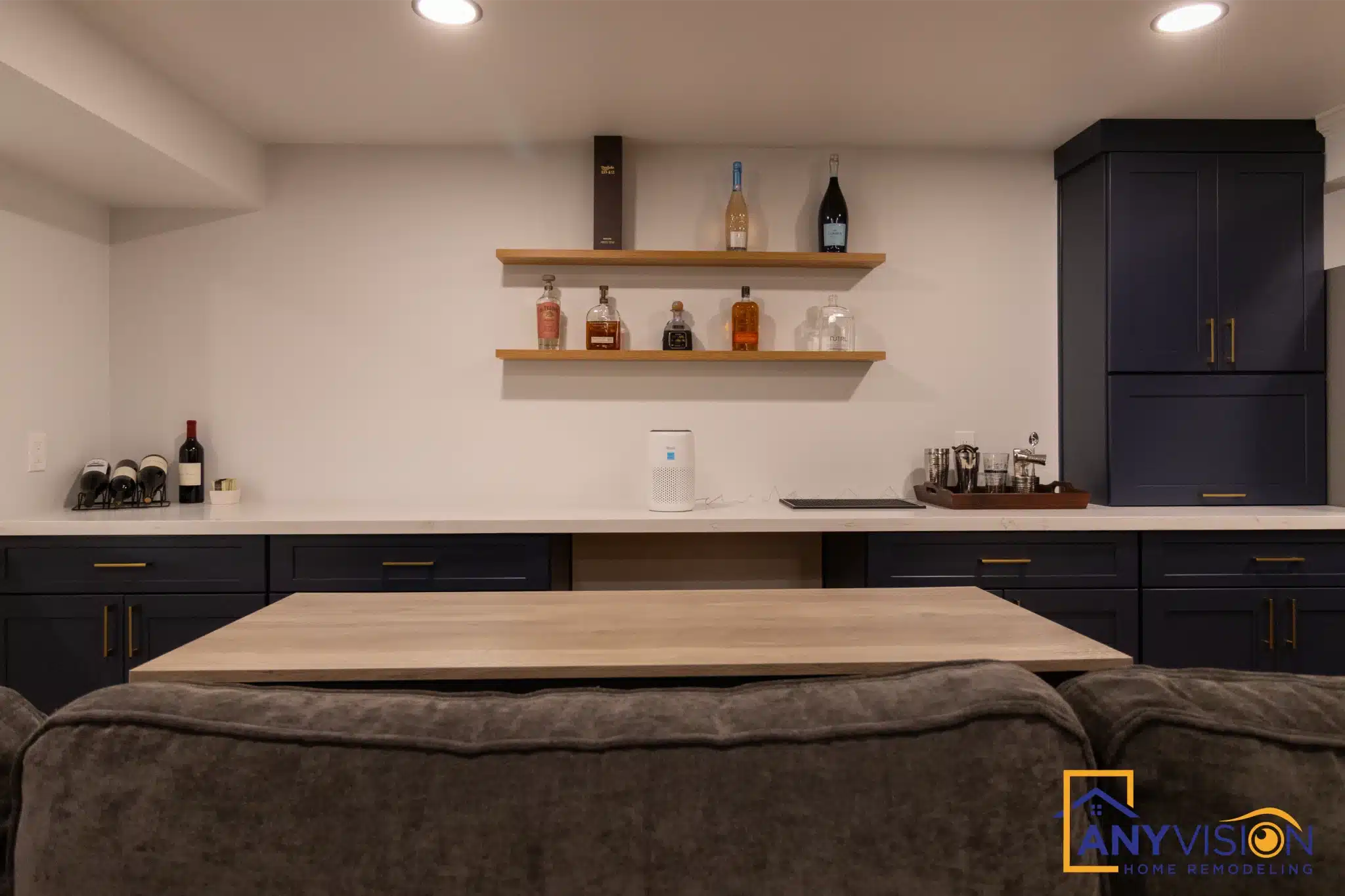 Basement kitchenette with navy cabinetry and waterfall counter