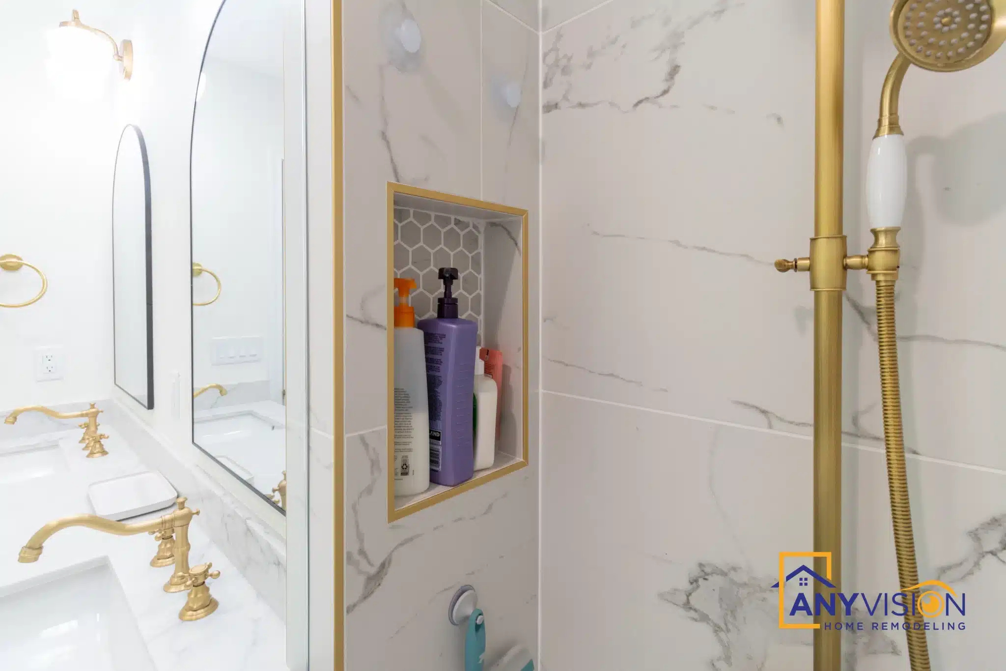 Brass shower fittings and handheld against white marble-look slab