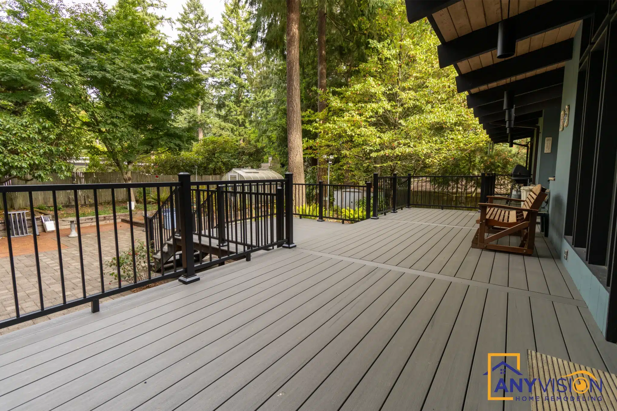 Slim black metal balusters along the open deck edge with trees beyond