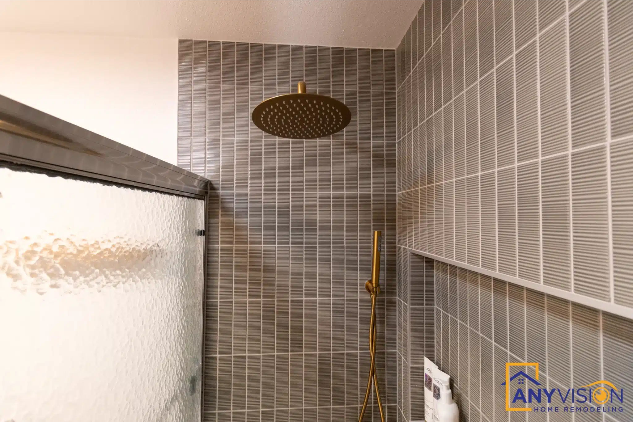 Brushed brass rainfall head and shower controls against stacked green tile
