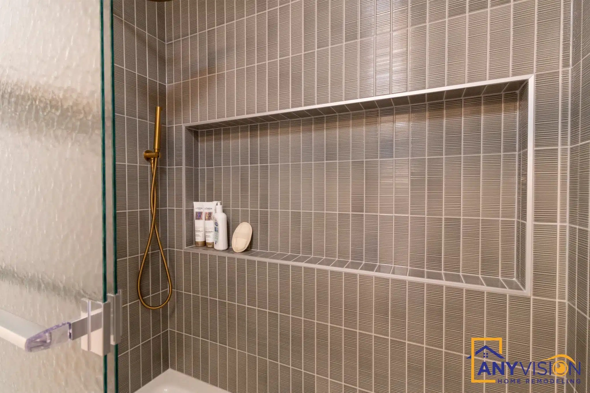 Recessed niche framed in brushed brass, set into the stacked green tile