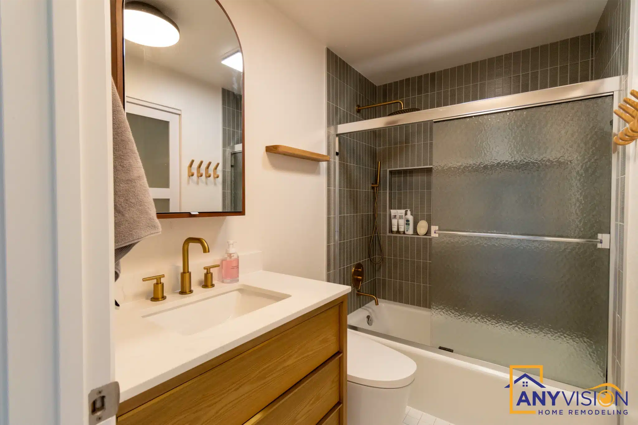 Bathroom remodel with a wood vanity and brushed brass fittings in North Seattle