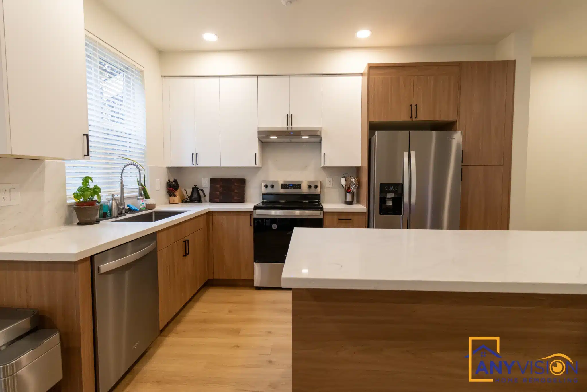 Kitchen with white uppers, wood base cabinets and the window over the sink