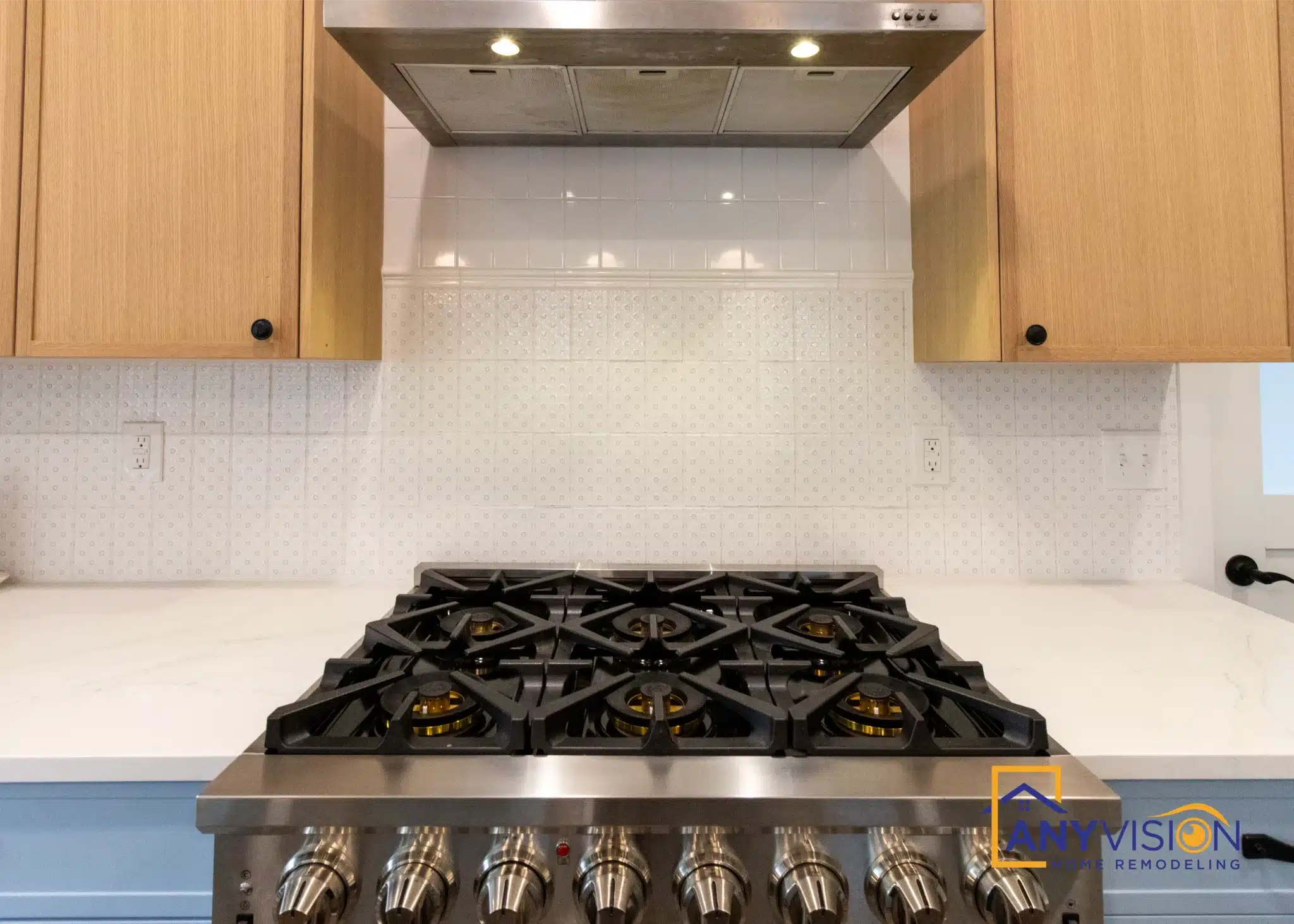 Pro gas range beneath a timber-clad extraction hood with slab backsplash behind