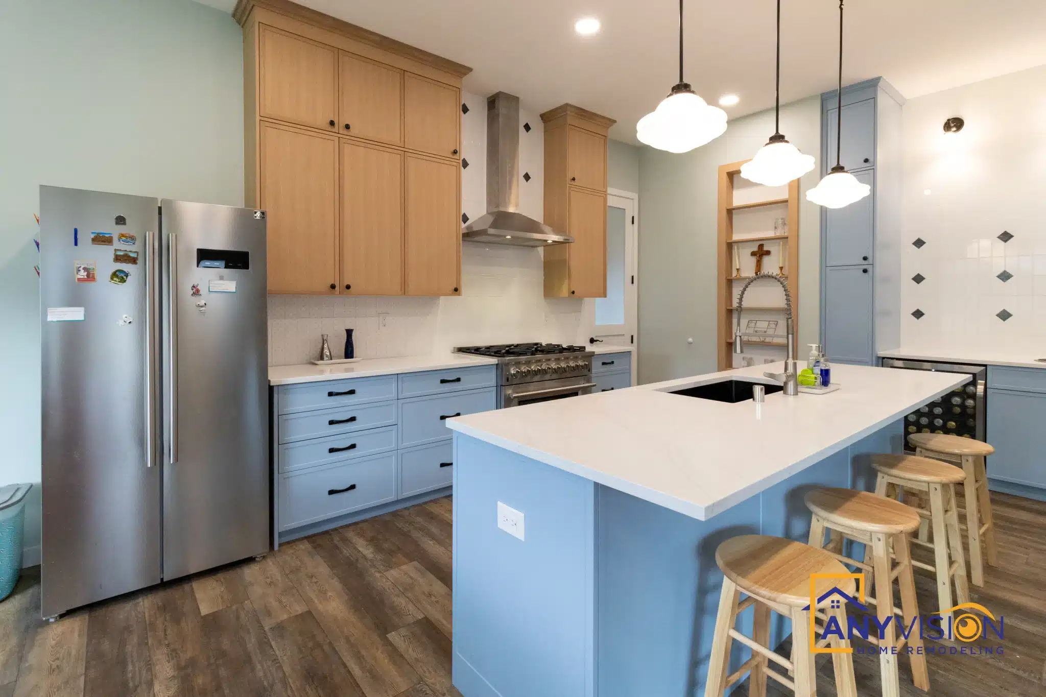 Refrigerator and wood upper cabinetry beside the island