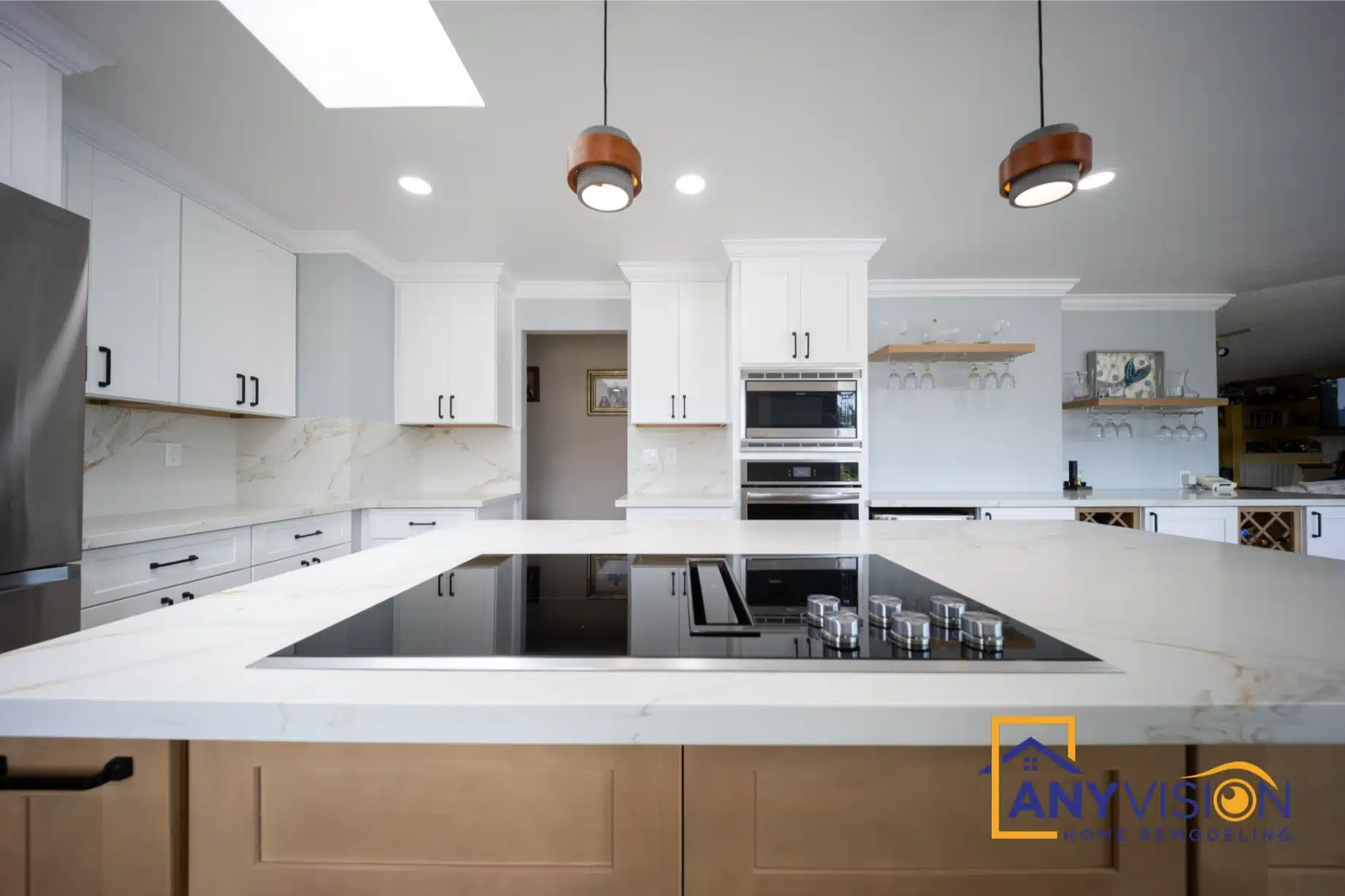 Wood-fronted island with waterfall quartz ends against white perimeter cabinetry
