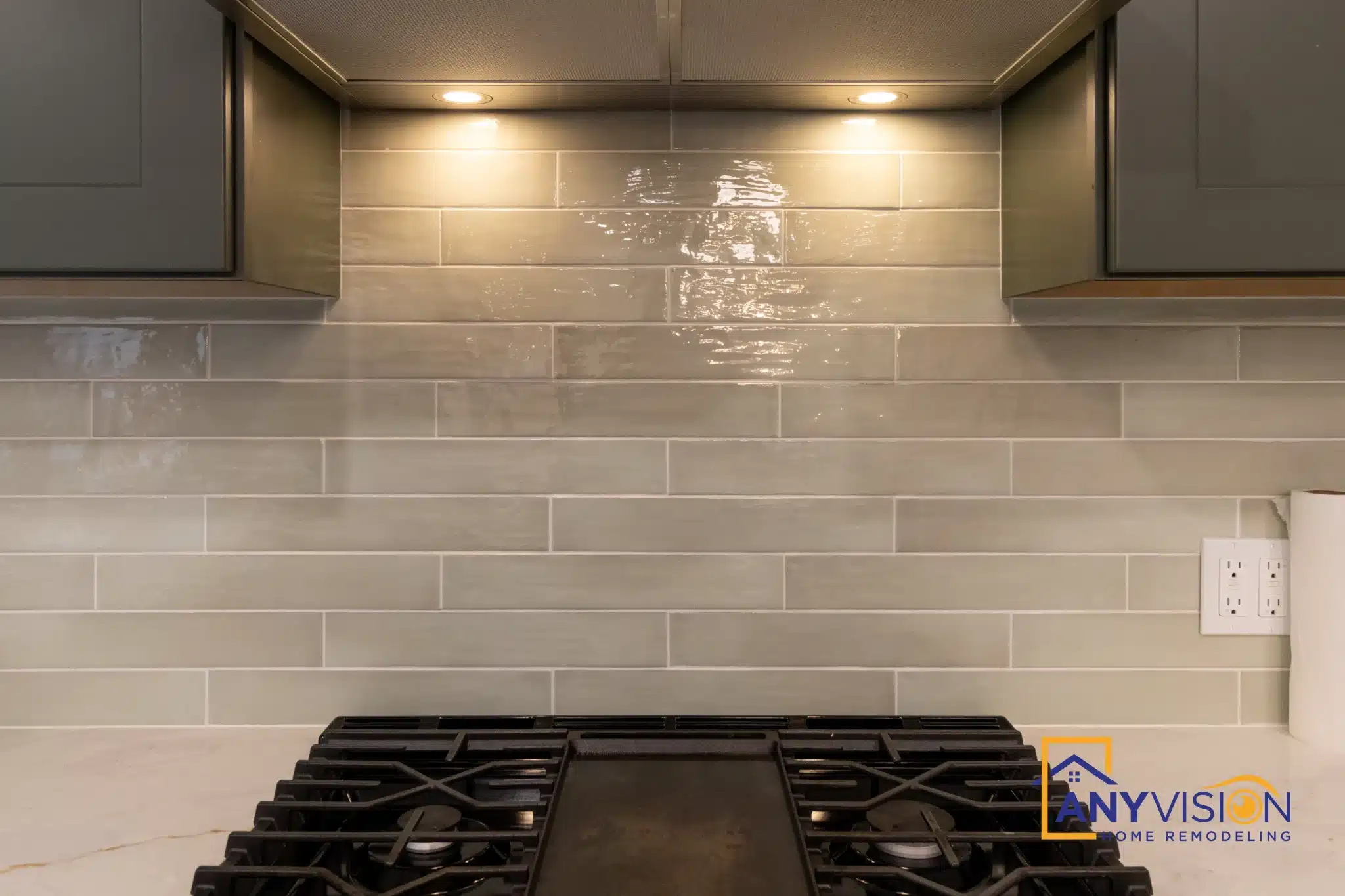 Gas range beneath a stainless hood against the stacked tile backsplash