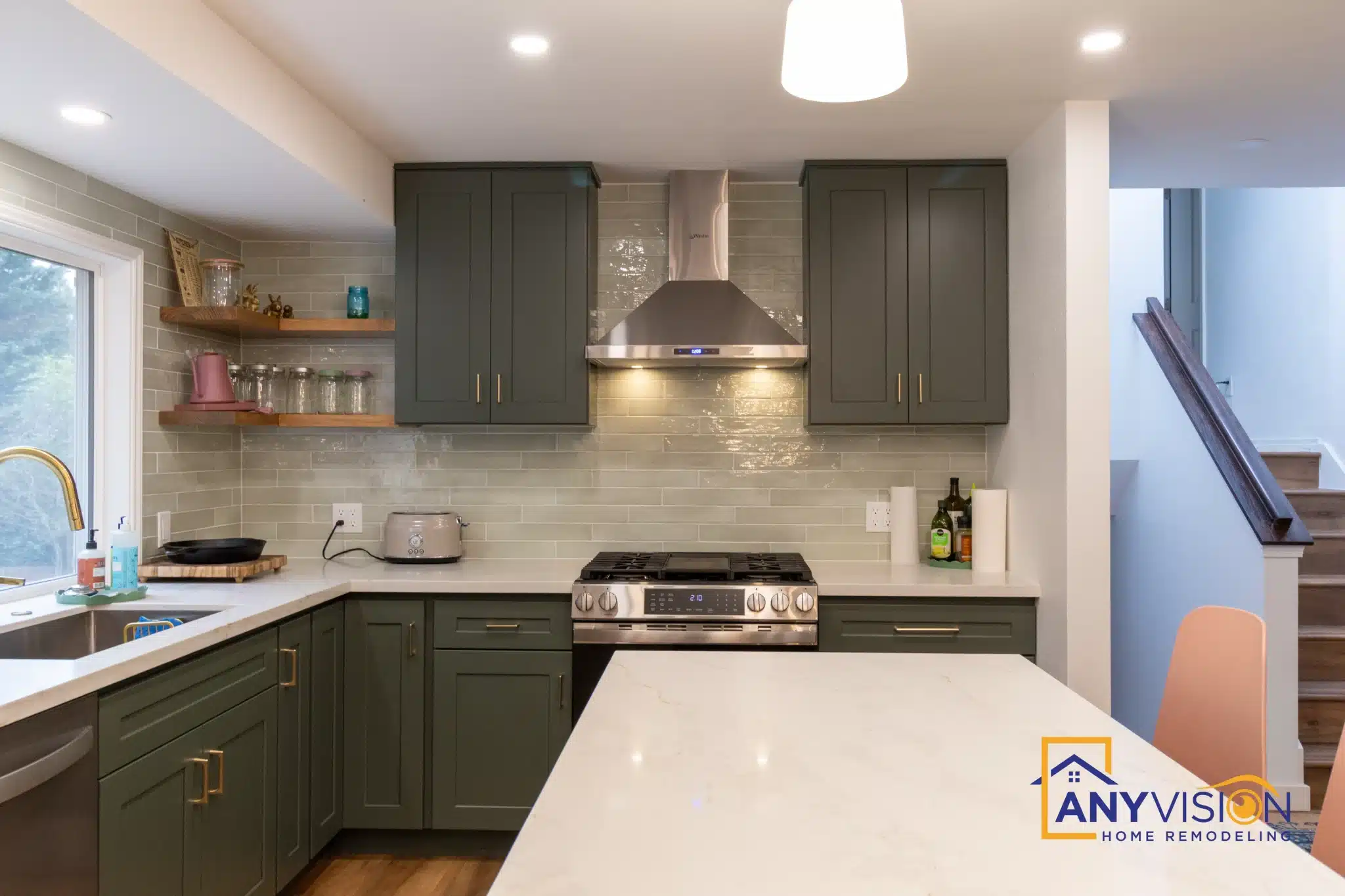 Deep green cabinetry with brass hardware and white counters