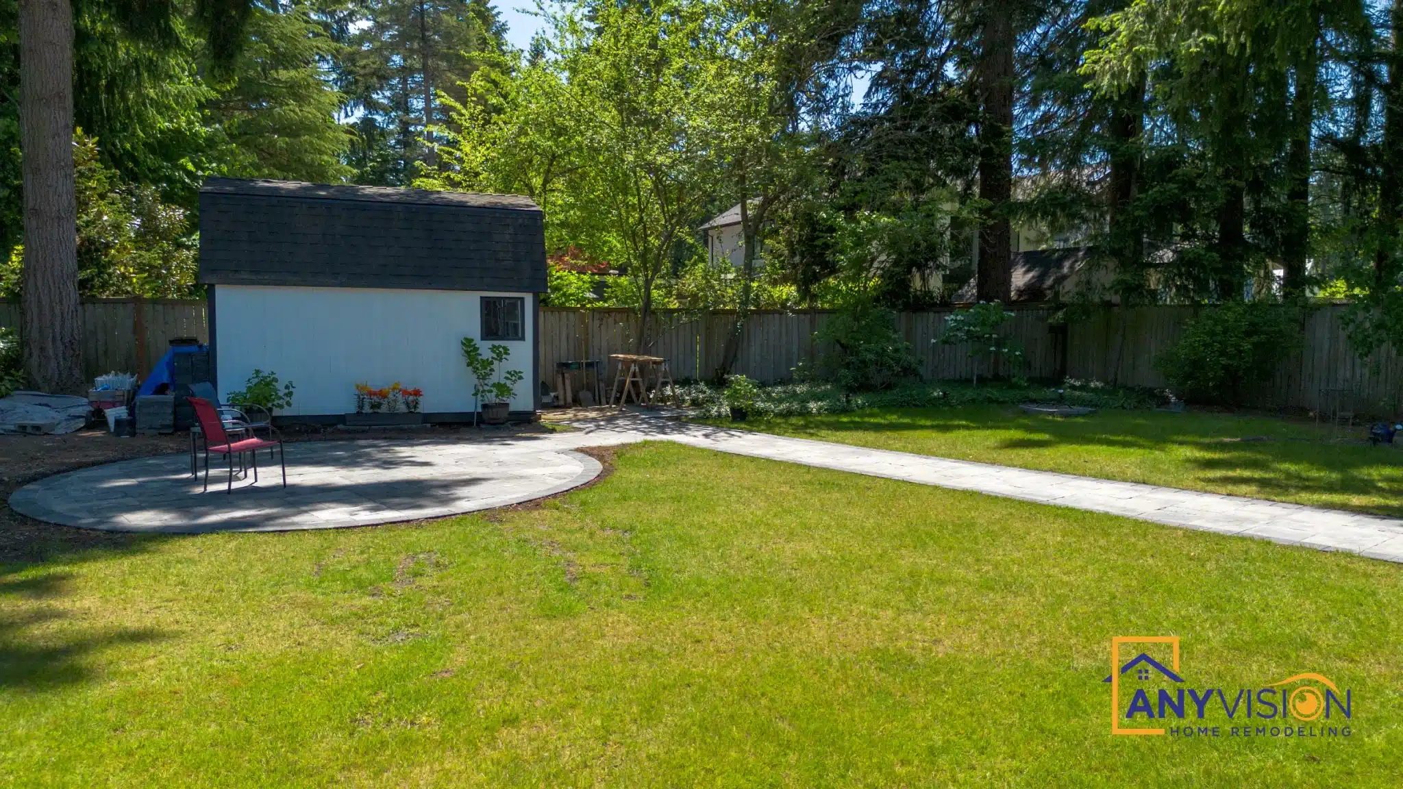 Paver patio and retaining wall beside a mature conifer