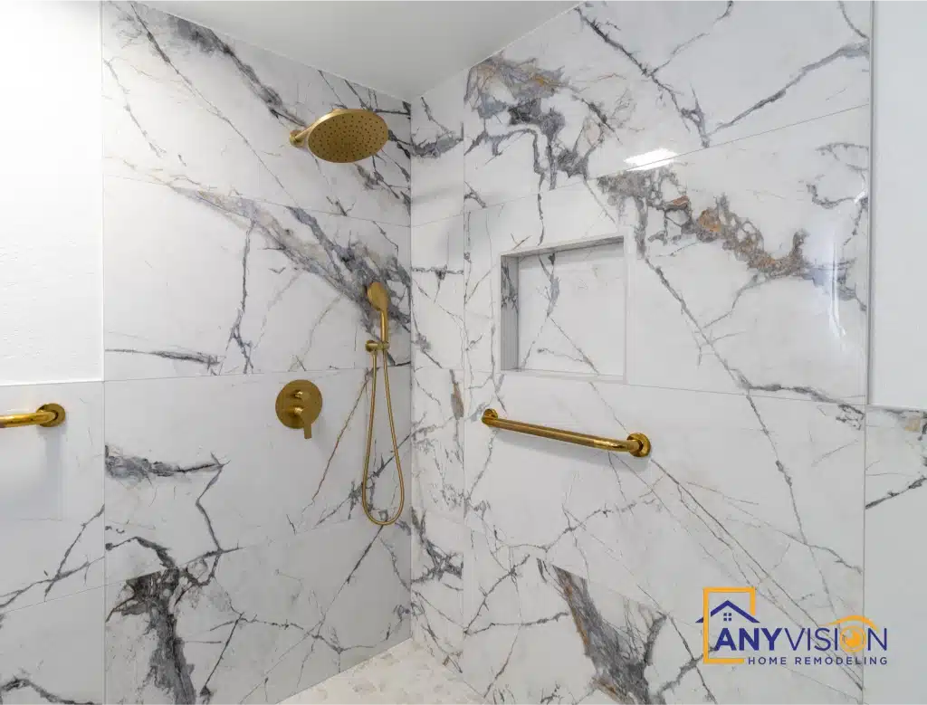 Roll-in shower with brass grab bars and handheld against marble-look slab walls