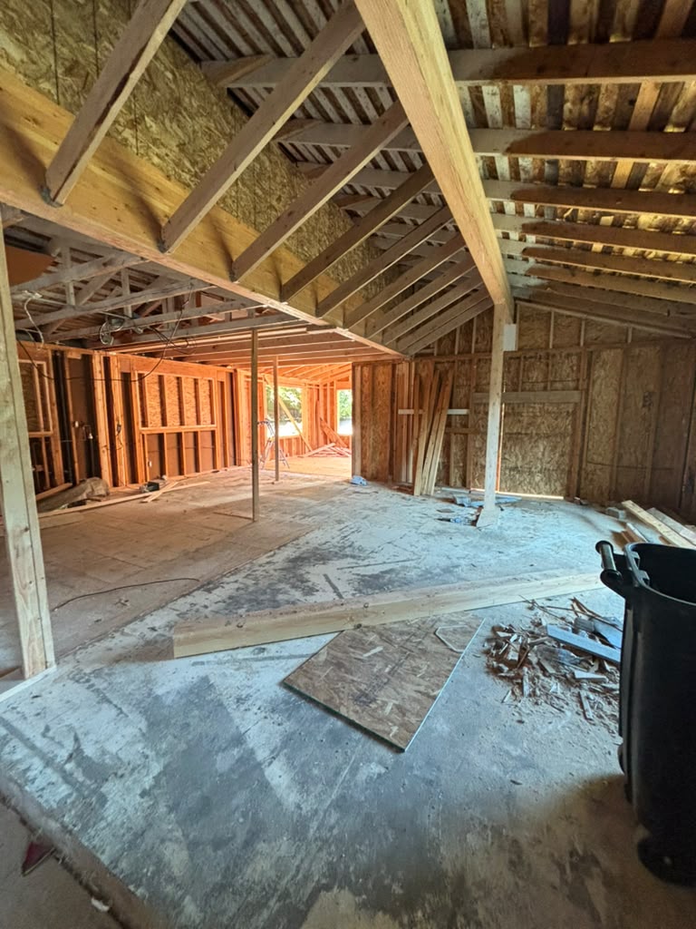 Interior of a Redmond home gutted to the studs, exposing original wall framing and ceiling trusses during a full home remodel