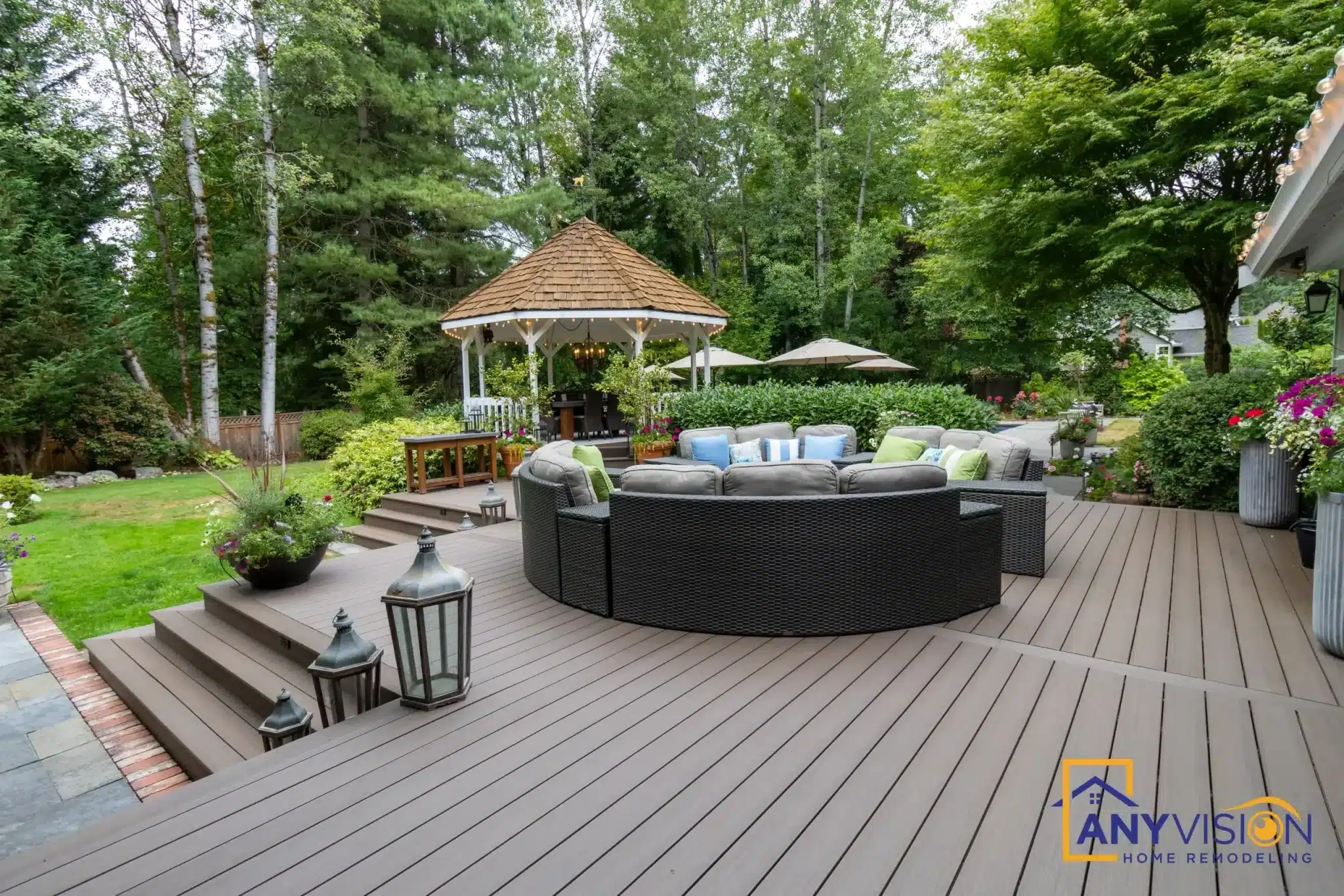 Gray composite deck with curved black wicker sectional sofa, steps, gazebo, and mature trees
