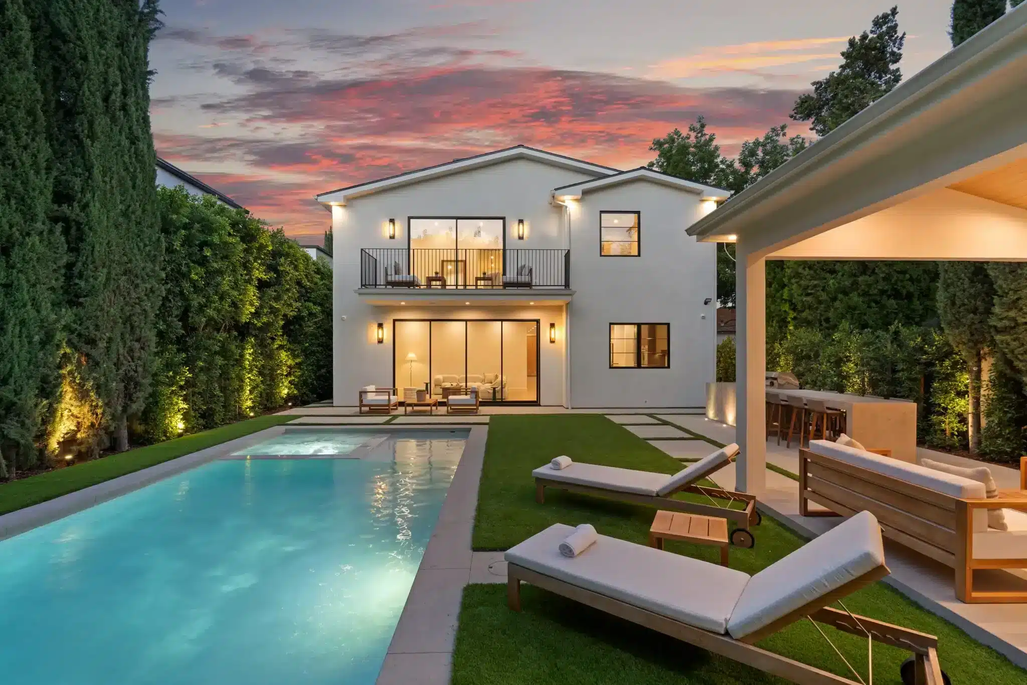 Two-story home with an illuminated pool and landscaped yard at twilight, Bellevue, WA