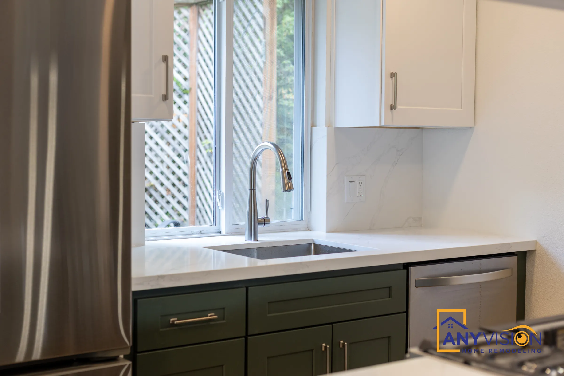 Undermount sink under a window with deep green shaker base cabinets and white uppers