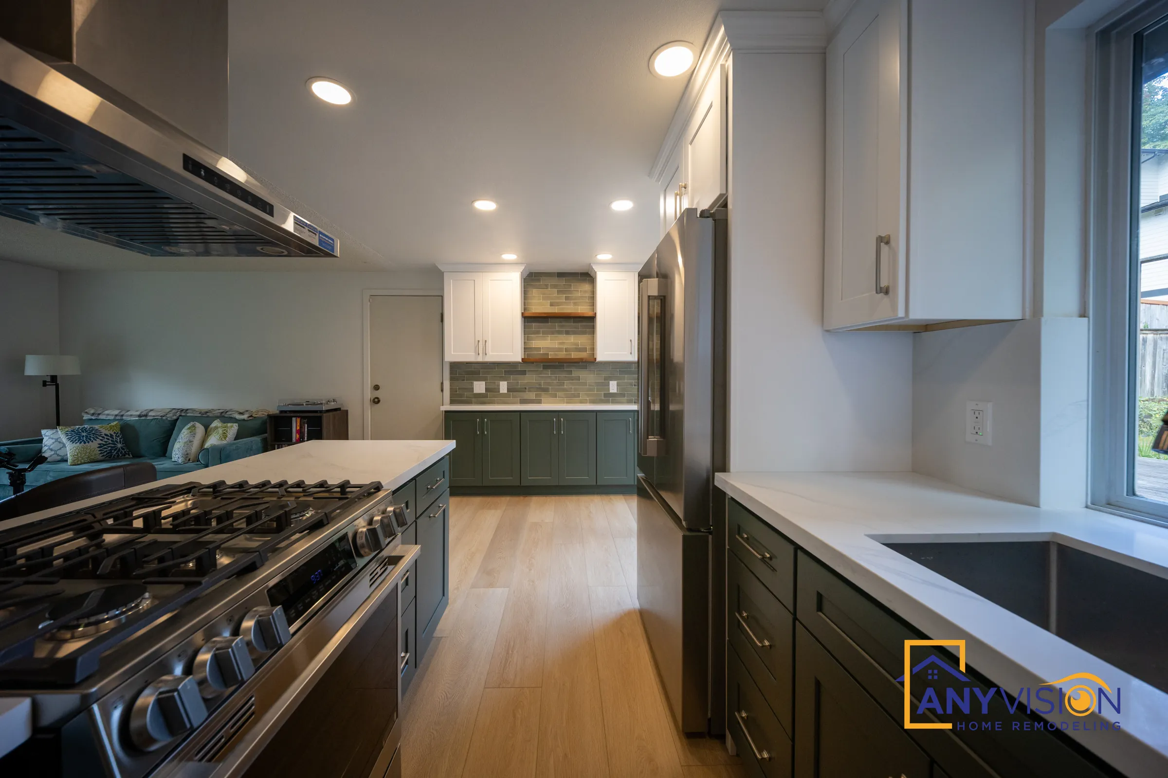 Gas range and long counter run with green cabinets and white quartz-look tops