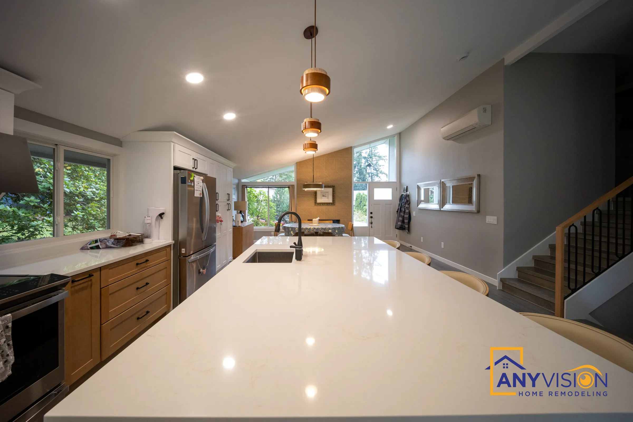 Long quartz island with an undermount sink and black faucet under copper pendants