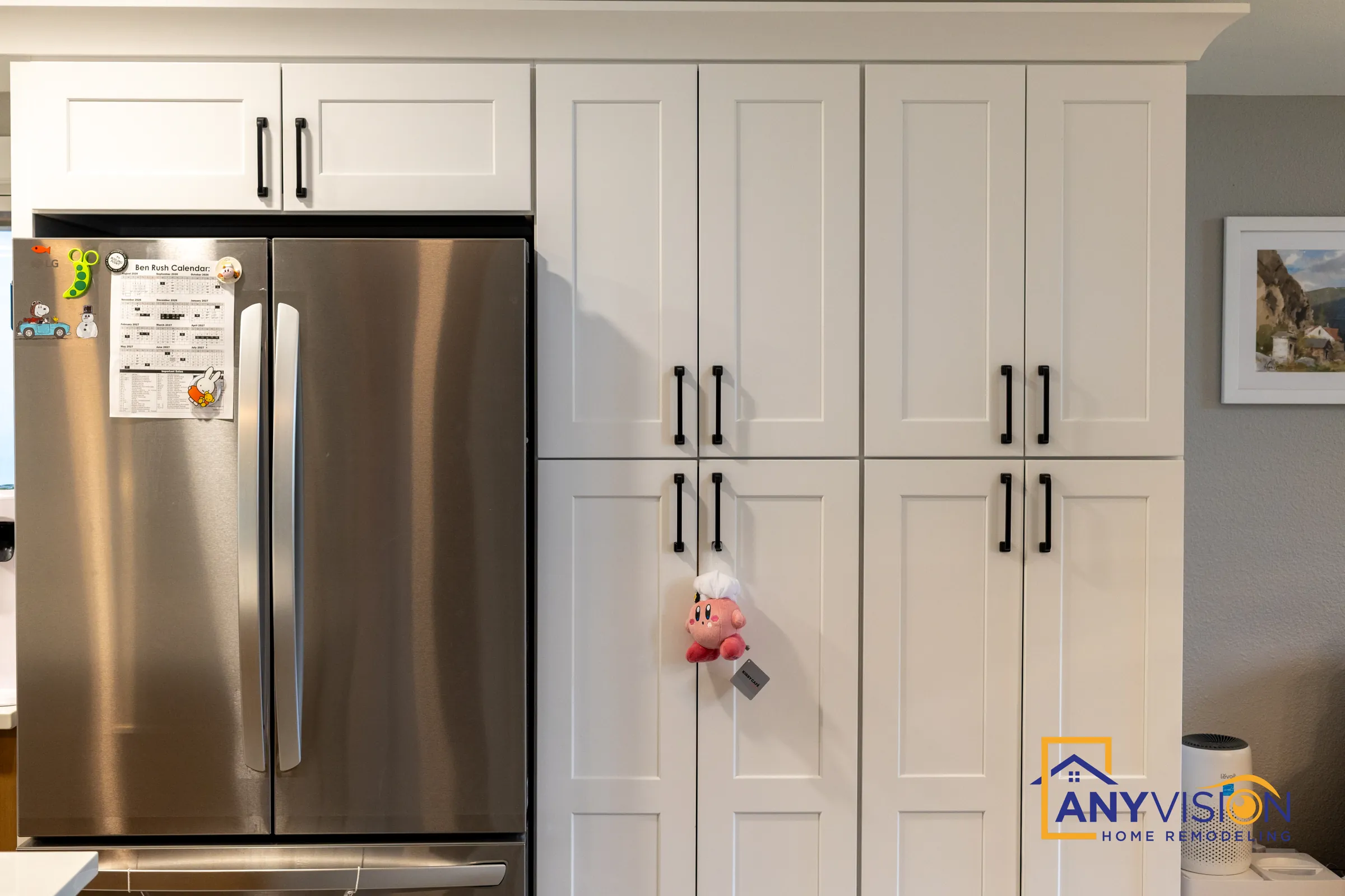 Full-height white shaker pantry wall beside a stainless French-door refrigerator