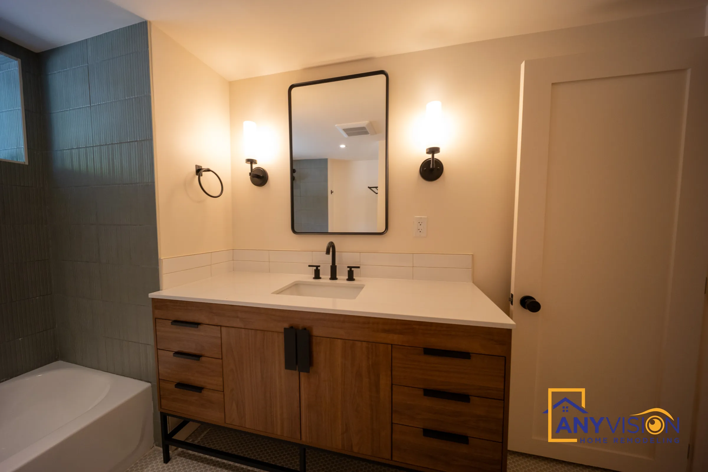 Floating walnut-tone vanity on a black metal frame with wall sconces