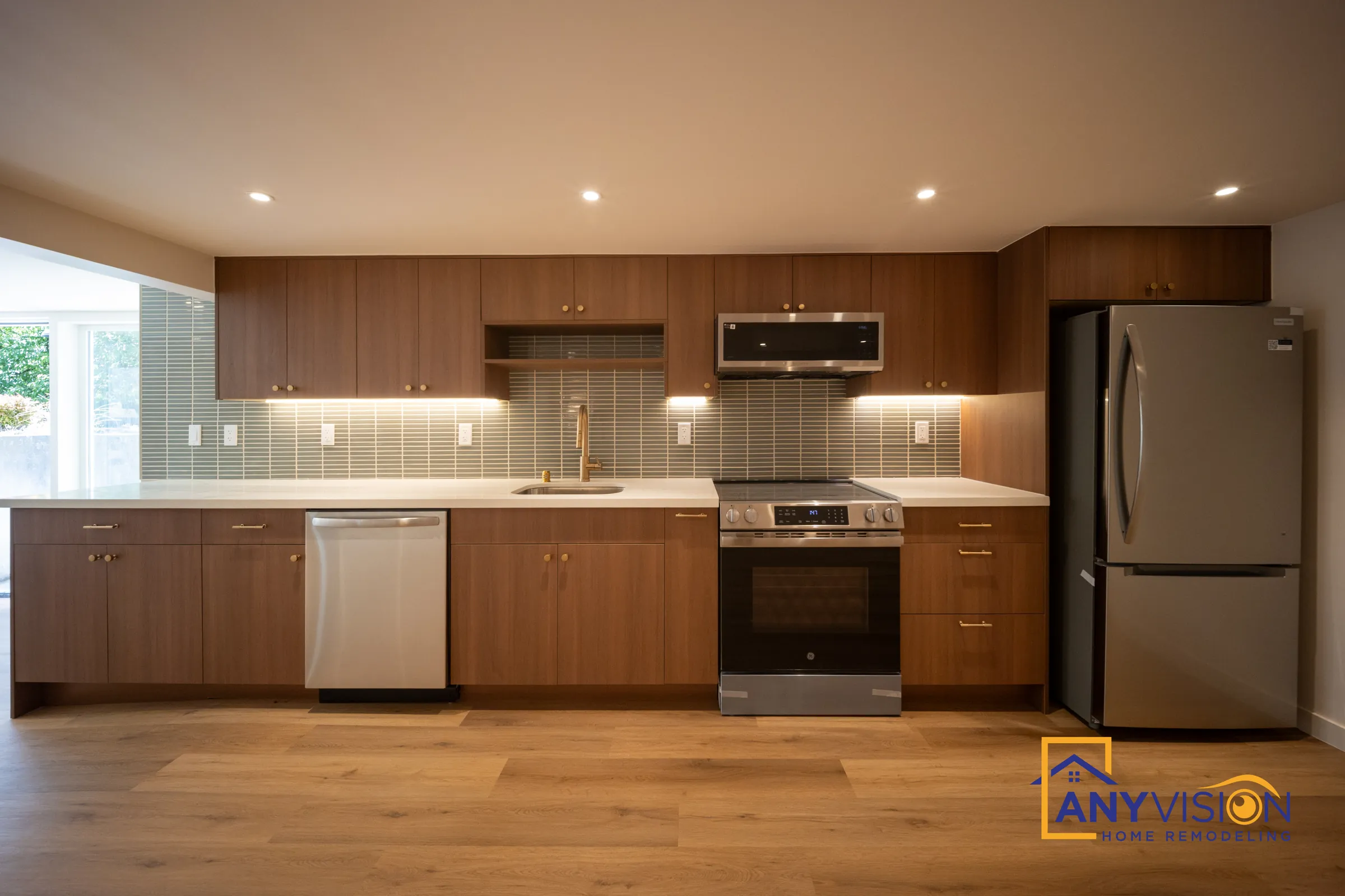 Full basement kitchen with walnut-tone cabinets, green glass backsplash and stainless appliances