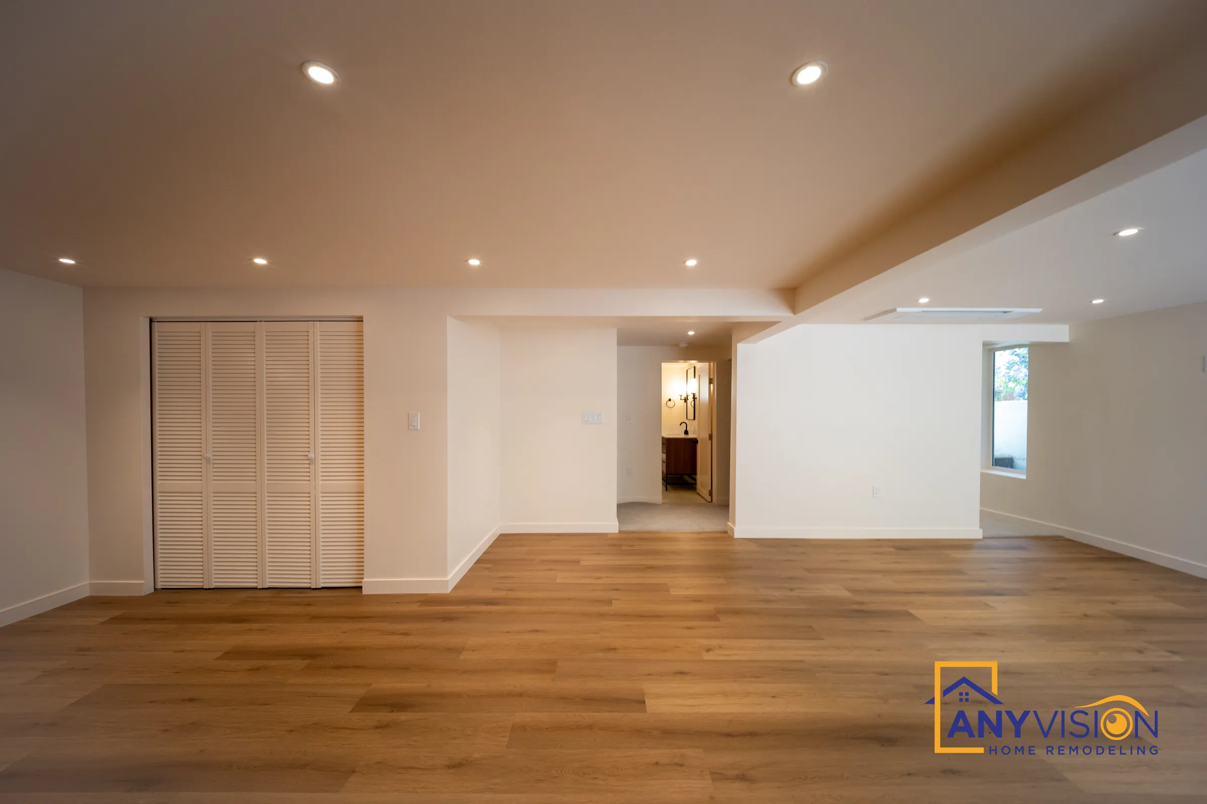 Open living area with wood-look flooring and recessed lights