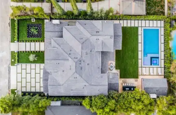Aerial view of modern home exterior remodelling with geometric roof design, backyard pool, and landscaped garden.