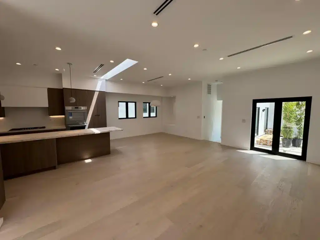 Spacious modern kitchen and living area with skylight, wood floors, and large patio doors built by basement contractor.