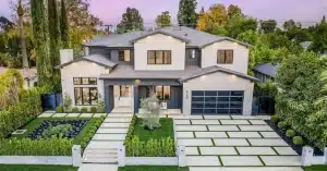 Modern two-story house with gray and white exterior, large windows, and landscaped front yard after home exterior remodelling.